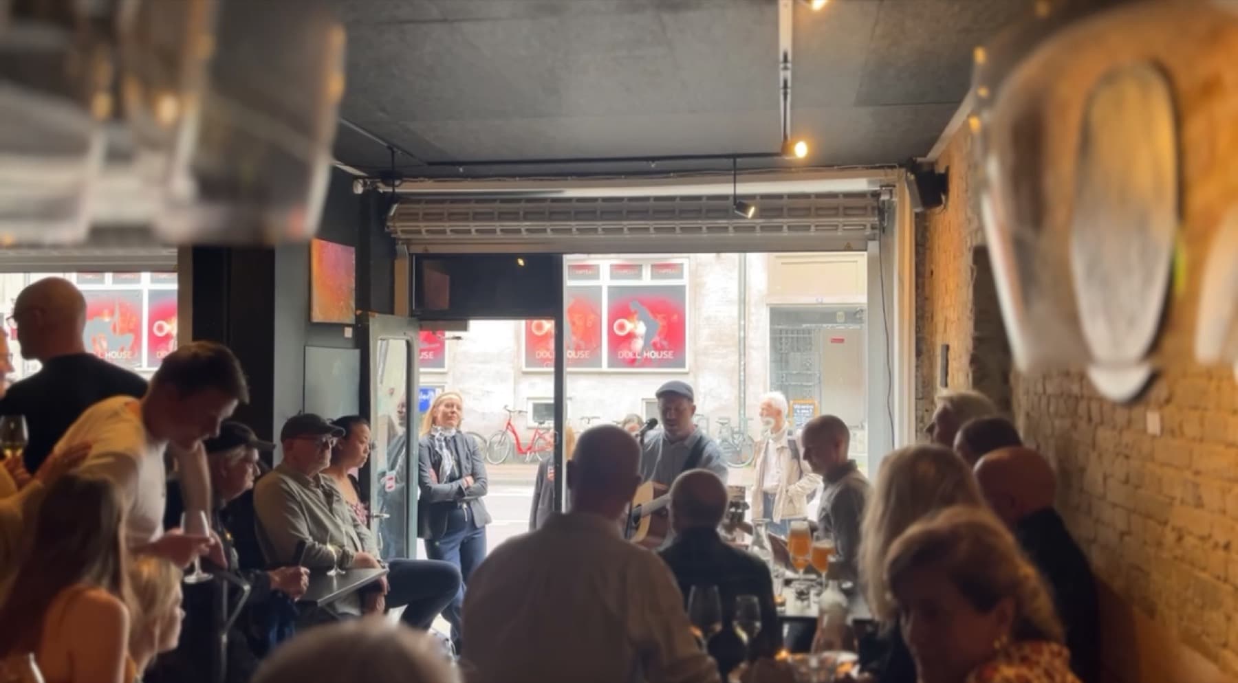 Fyldt lokale i Vesterhus med publikum tæt på musikeren og porten åben ud mod Istedgade